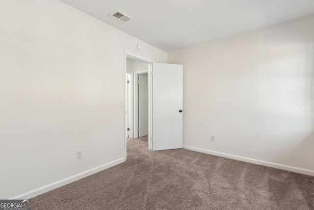 empty room featuring carpet floors, visible vents, and baseboards