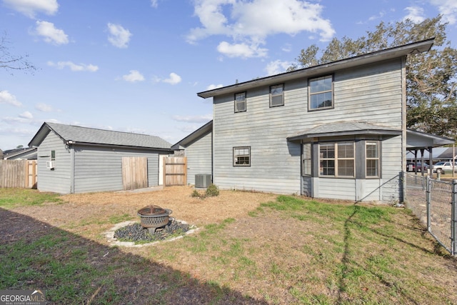 back of property with an outdoor fire pit, fence, an outbuilding, and central air condition unit