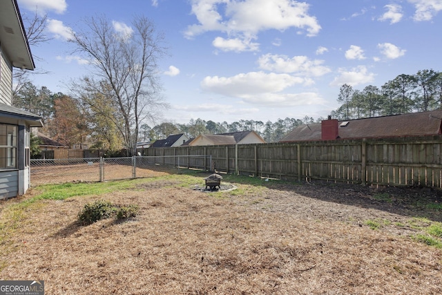 view of yard with a fenced backyard and a fire pit