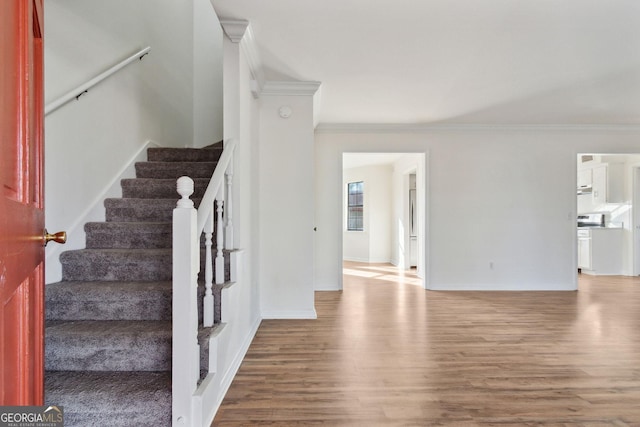 stairway with crown molding, baseboards, and wood finished floors