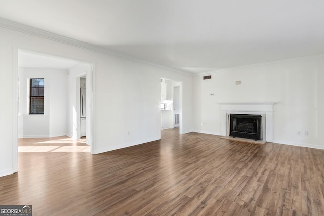 unfurnished living room featuring a fireplace with flush hearth, visible vents, crown molding, and wood finished floors