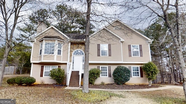 split foyer home with stone siding and a chimney