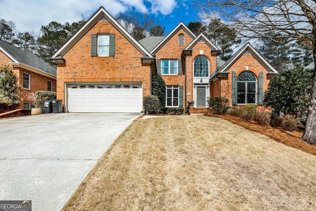 traditional-style home with a garage, concrete driveway, brick siding, and a front yard