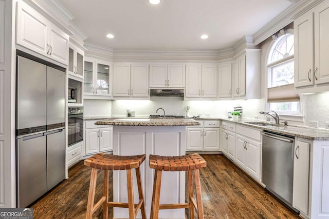 kitchen featuring dark wood finished floors, appliances with stainless steel finishes, white cabinets, a sink, and under cabinet range hood