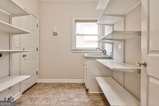 interior space with laundry area, baseboards, and a sink