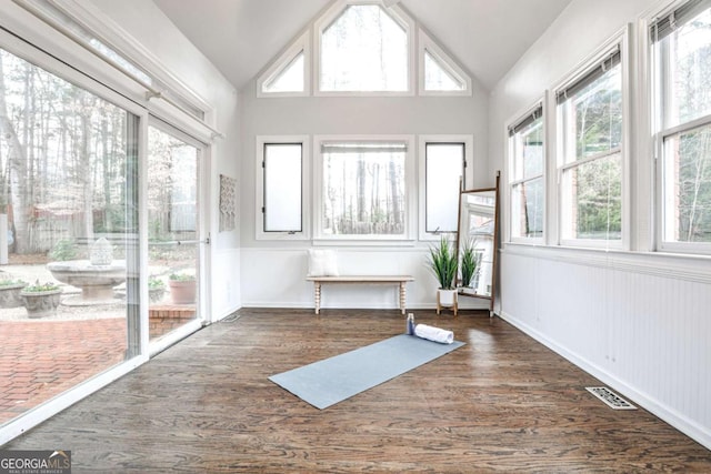 workout area featuring lofted ceiling, wood finished floors, visible vents, and baseboards