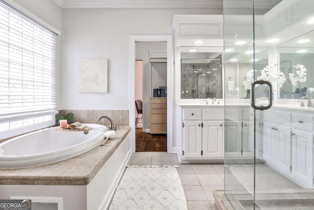 bathroom with a healthy amount of sunlight, a garden tub, tile patterned flooring, and vanity