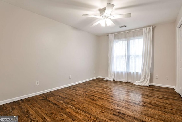 unfurnished room featuring dark wood-style floors, visible vents, and baseboards