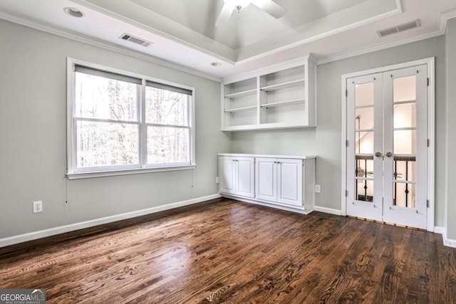 empty room with dark wood-style floors, baseboards, visible vents, and a tray ceiling