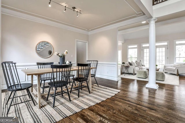 dining space featuring track lighting, a wainscoted wall, wood finished floors, ornate columns, and crown molding