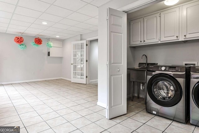 laundry area featuring cabinet space, washing machine and dryer, light tile patterned flooring, a sink, and baseboards