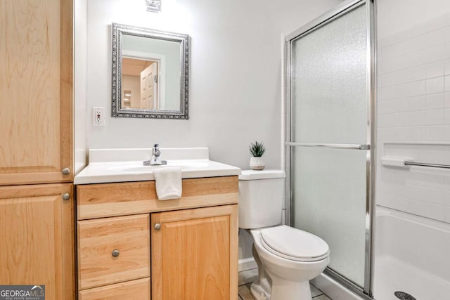 bathroom featuring vanity, an enclosed shower, and toilet