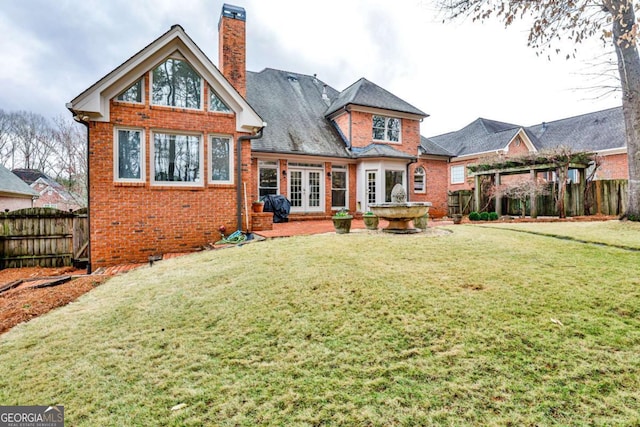 rear view of house featuring a yard, brick siding, a chimney, and french doors