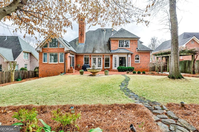 view of front facade with brick siding, fence, a chimney, and a front lawn