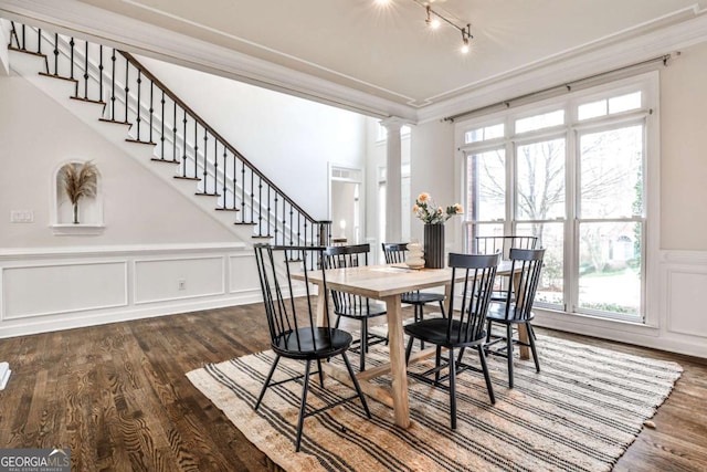 dining space featuring dark wood-type flooring, crown molding, and ornate columns