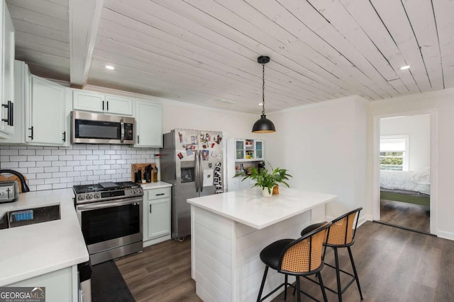 kitchen with a sink, light countertops, appliances with stainless steel finishes, decorative backsplash, and dark wood-style floors