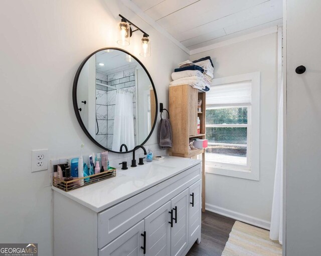 bathroom featuring baseboards, a shower with shower curtain, wood finished floors, crown molding, and vanity