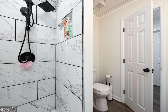 full bath with tiled shower, visible vents, toilet, and wood finished floors