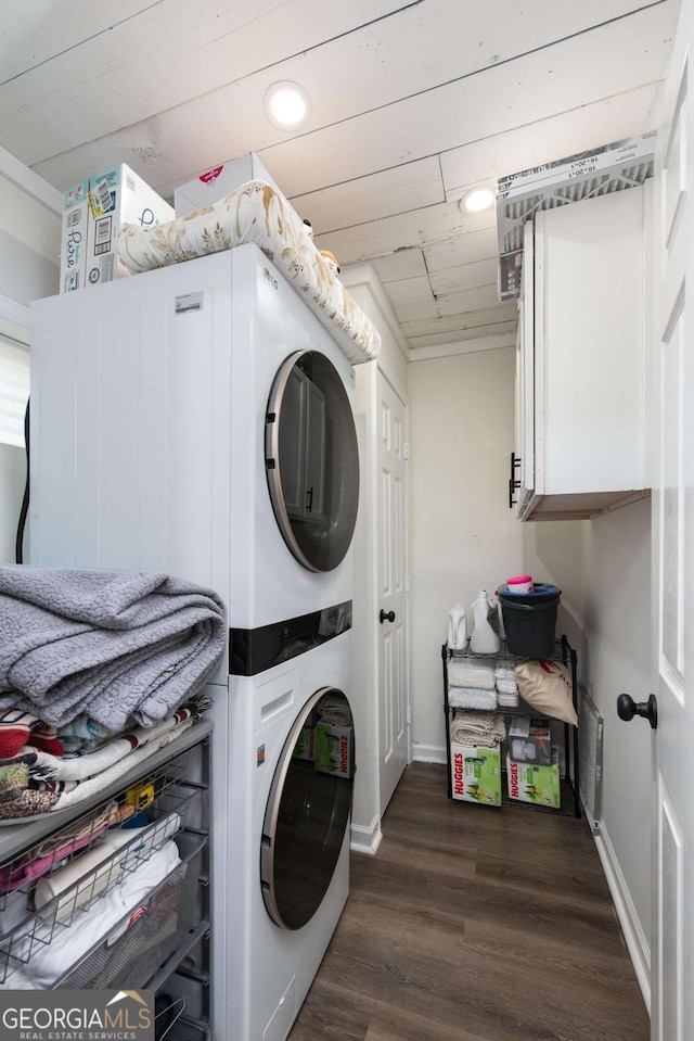 clothes washing area featuring recessed lighting, dark wood-type flooring, baseboards, stacked washer / drying machine, and cabinet space