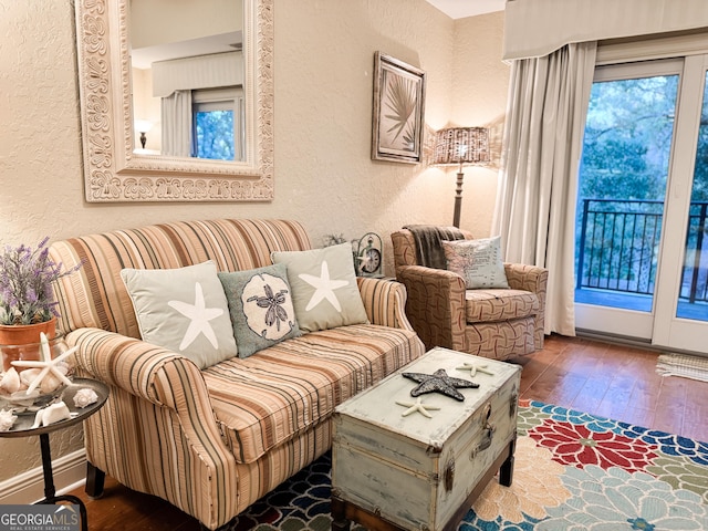 sitting room featuring a textured wall, baseboards, and hardwood / wood-style flooring