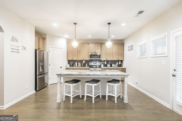 kitchen with arched walkways, visible vents, backsplash, appliances with stainless steel finishes, and a kitchen island with sink