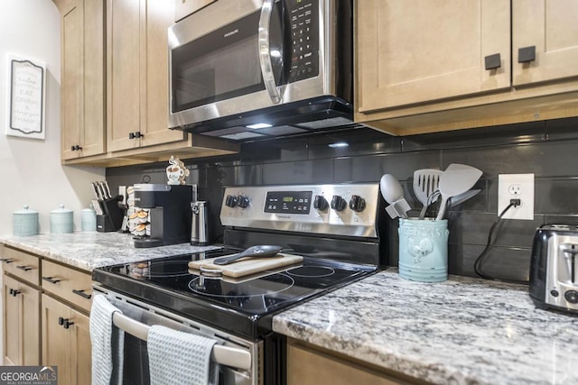 kitchen with light stone countertops, light brown cabinets, stainless steel appliances, and backsplash