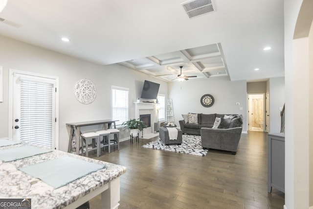 living area featuring ceiling fan, coffered ceiling, a fireplace, visible vents, and dark wood-style floors