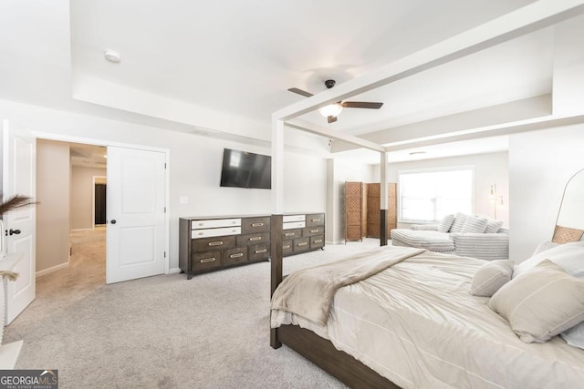 bedroom with a ceiling fan, a raised ceiling, and light carpet