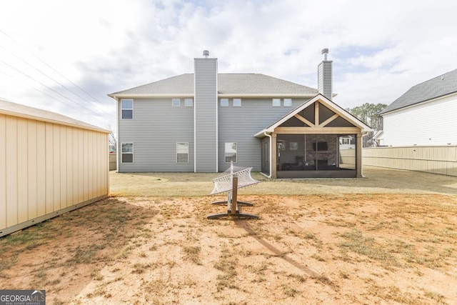 back of property with a sunroom, a chimney, and fence