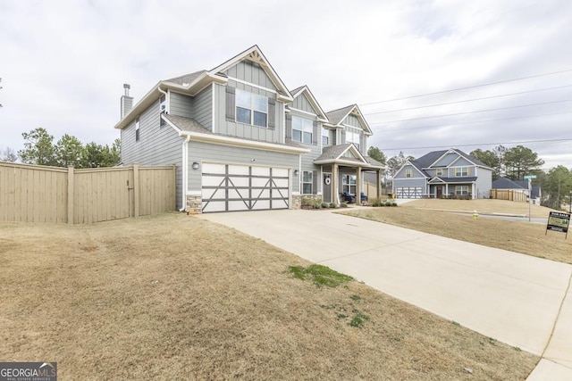 craftsman-style home with a garage, concrete driveway, stone siding, fence, and board and batten siding