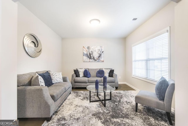 living room with wood finished floors, visible vents, and baseboards