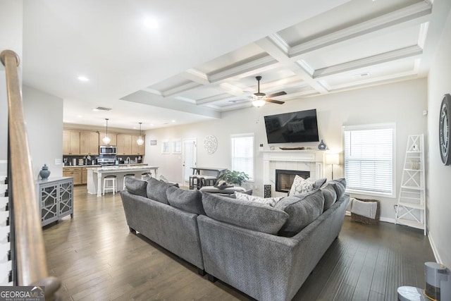 living room with plenty of natural light, a fireplace, coffered ceiling, and dark wood-style floors