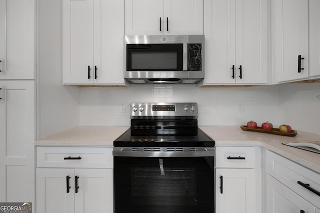 kitchen featuring stainless steel appliances, white cabinetry, light stone counters, and decorative backsplash