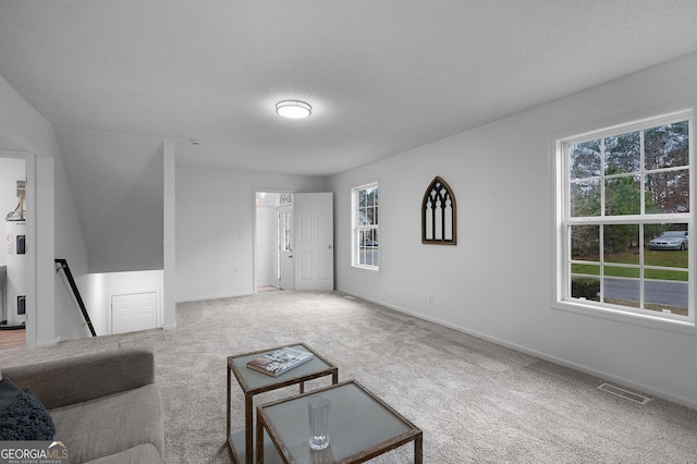 living room with carpet floors, visible vents, a textured ceiling, and baseboards