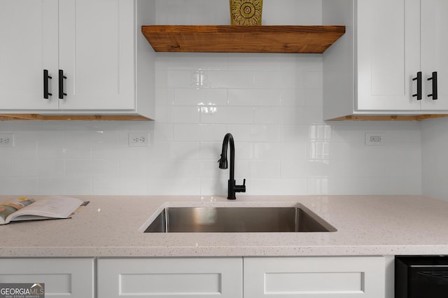 kitchen featuring tasteful backsplash, white cabinetry, a sink, and exhaust hood