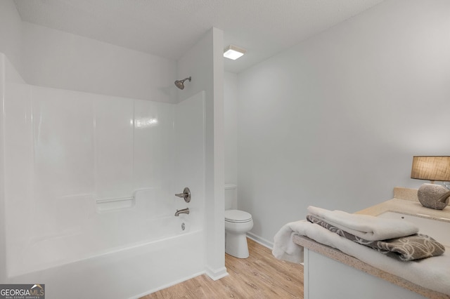 bathroom with shower / bathtub combination, toilet, vanity, wood finished floors, and baseboards