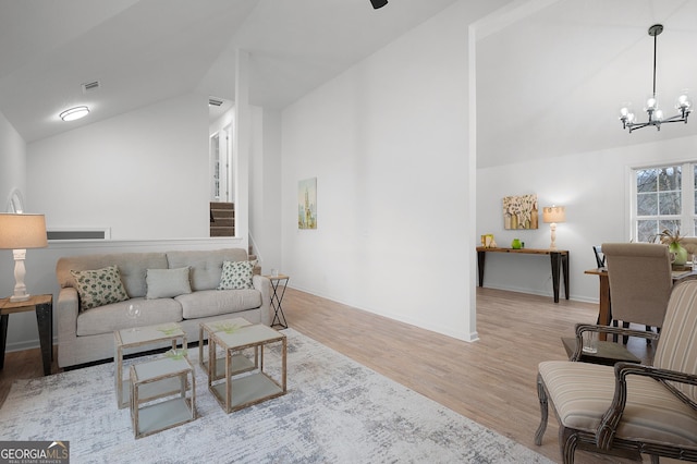 living area featuring lofted ceiling, baseboards, a notable chandelier, and light wood finished floors