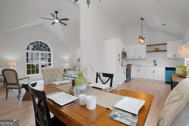 dining room featuring light wood-style floors, visible vents, high vaulted ceiling, and a ceiling fan