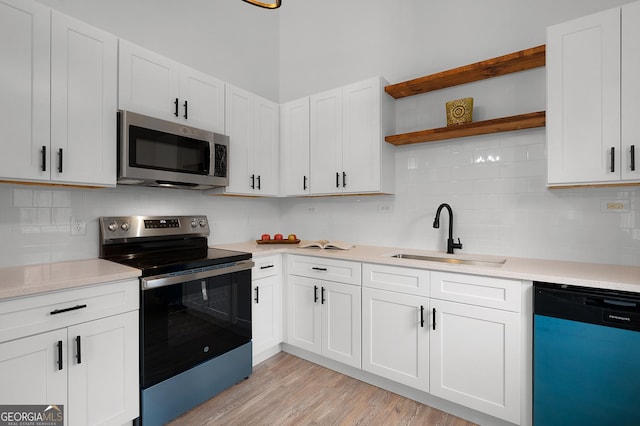 kitchen featuring open shelves, stainless steel appliances, light countertops, white cabinetry, and a sink