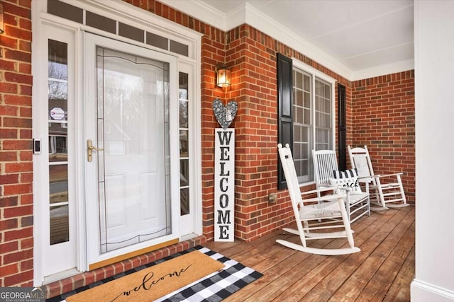 doorway to property with a porch and brick siding