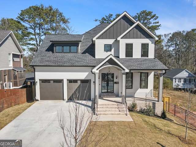 view of front of house with roof with shingles, board and batten siding, fence, a garage, and driveway