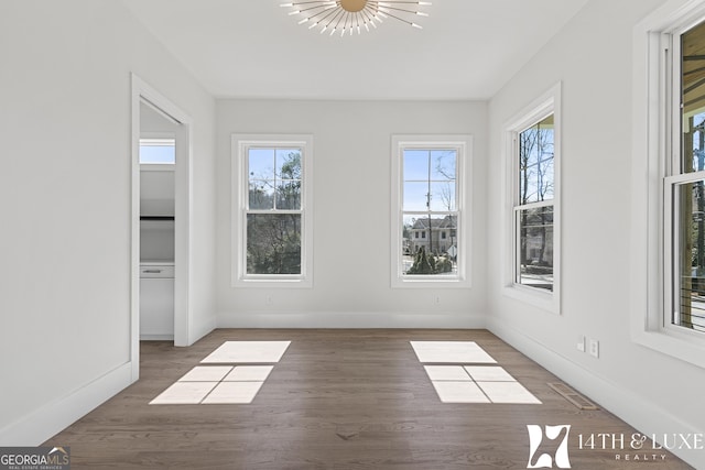 interior space featuring visible vents, wood finished floors, a wealth of natural light, and an inviting chandelier