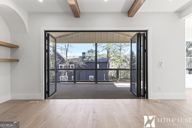 interior space featuring beam ceiling, baseboards, and wood finished floors