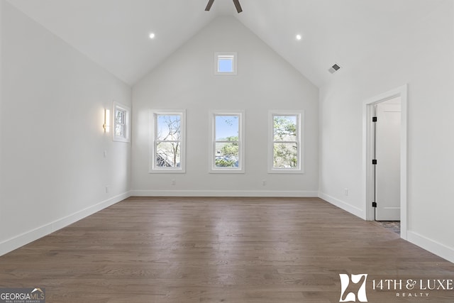 unfurnished living room with a healthy amount of sunlight, high vaulted ceiling, and dark wood finished floors