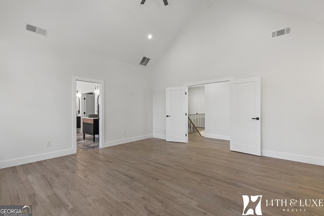 unfurnished bedroom with high vaulted ceiling, wood finished floors, visible vents, and baseboards