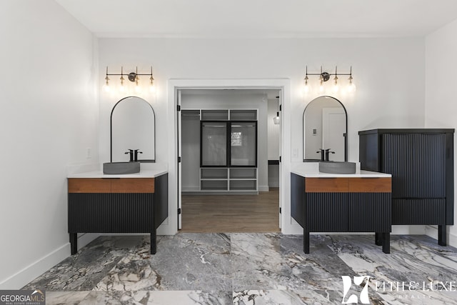 bathroom with marble finish floor, two vanities, and baseboards