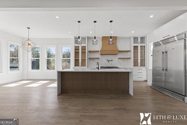 kitchen featuring white cabinets, custom range hood, open shelves, and built in fridge