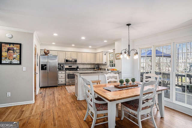 dining area with light wood finished floors, a chandelier, baseboards, and ornamental molding