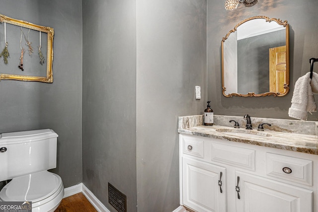 bathroom featuring visible vents, toilet, wood finished floors, baseboards, and vanity