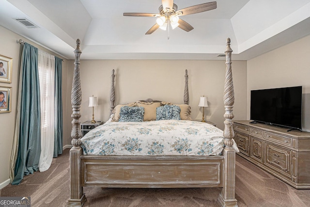 bedroom with a tray ceiling, visible vents, carpet floors, and ceiling fan